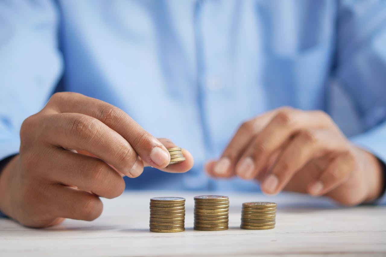 about-02 Close-up of hands stacking gold coins, symbolizing financial growth and savings.